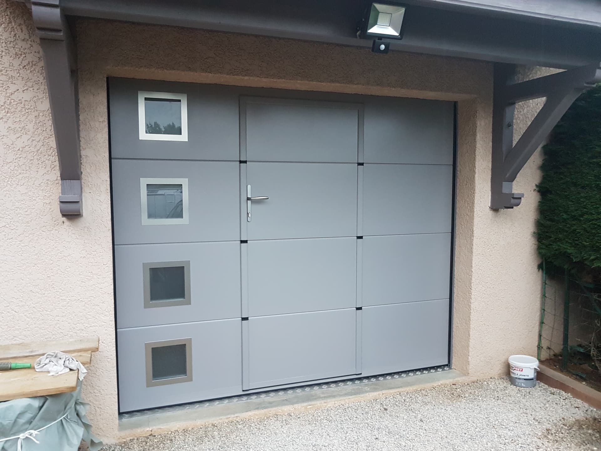 Porte de garage sectionnelle vitree installee par THERA Fermetures